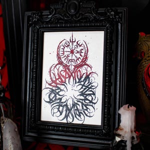 May include: Black framed print with a white background and a red and black design. The design features a compass with a circle of runes around it. The runes are in a circular pattern and are in black. The compass is in red and black. The design is surrounded by a black circle with a white background.