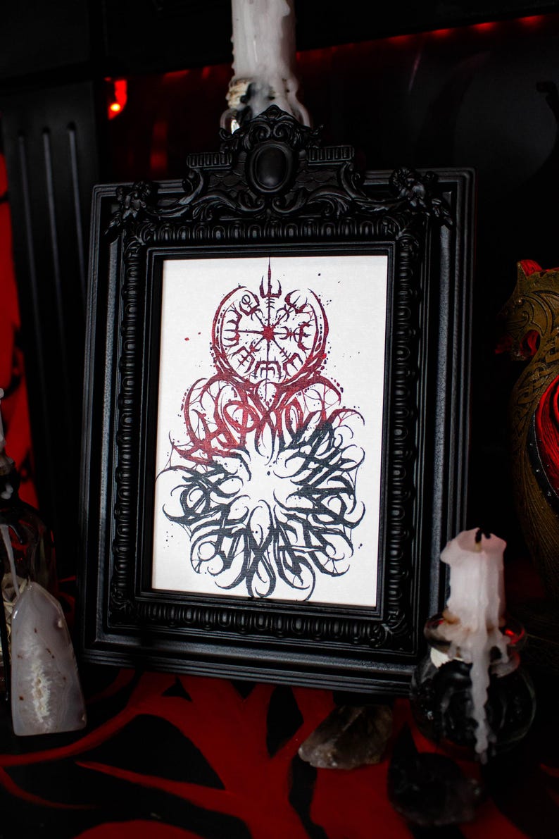 May include: Black framed print with a white background and a red and black design. The design features a compass with a circle of runes around it. The runes are in a circular pattern and are in black. The compass is in red and black. The design is surrounded by a black circle with a white background.