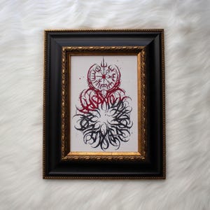 May include: A framed print with a black and red design. The design features a compass with a circle of text around it. The text is in a stylized font and is difficult to read.