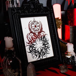 May include: A black framed print with a white background and a black and red design. The design features a compass with runes and a circle of stylized text.