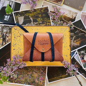 rustic natural leather envelope wrapped with a navy blue stripe and embossed with custom logo