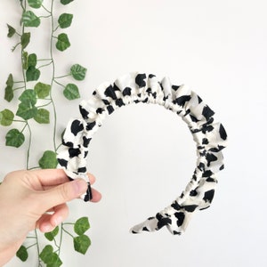 May include: A white and black patterned headband with a ruffled edge.