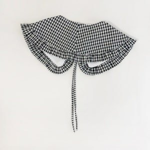 May include: A black and white gingham collar with a ruffled edge and a tie closure.