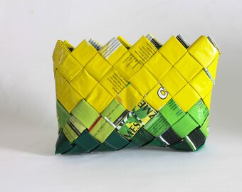 May include: A woven basket made from recycled materials. The basket is yellow and green and has a woven pattern. The basket is made from recycled materials.