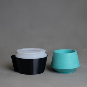May include: Two different sized planters, one black and one teal. The black planter has a white interior and a smooth, rounded top. The teal planter has a smooth, rounded top and a slightly flared base.