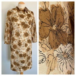 Peut inclure: Une robe vintage à imprimé floral brun et blanc avec un col montant et des manches trois quarts.