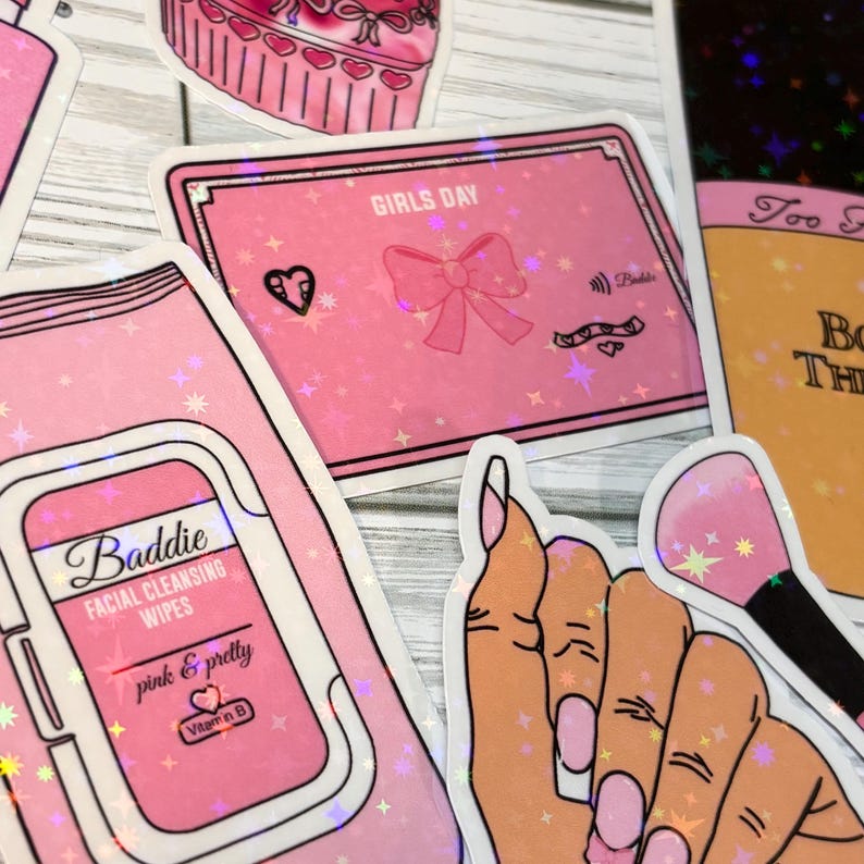 May include: A set of pink and white stickers with glitter accents. The stickers feature a makeup brush, a hand with manicured nails, a package of facial cleansing wipes, a cupcake, and a pink ribbon with the text "Girls Day".