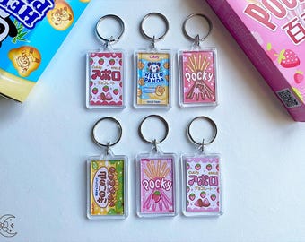 May include: Six colorful keychains featuring popular Japanese snacks. The keychains are made of clear plastic and feature images of Pocky, Hello Panda, and Apollo chocolate. The keychains are all attached to silver key rings.