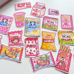 Op de afbeelding: Een verzameling kleurrijke stickers met Japanse snacks en drankjes. De stickers bevatten illustraties van populaire merken zoals Pocky, Calbee en Milky. De stickers zijn perfect om een ​​toets van Japanse kawaii toe te voegen aan je planner, laptop of telefoon.