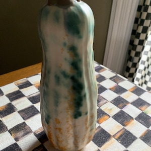 May include: A ceramic vase shaped like a gourd with a white glaze and green and yellow accents.
