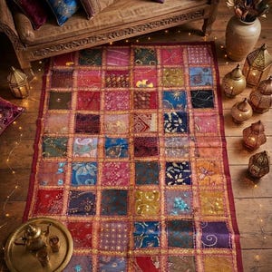 May include: A rectangular patchwork rug featuring a grid of multicolored fabric squares in shades of red, blue, gold, and green. Each square displays intricate embroidery, sequins, and floral patterns, all bordered by a dark red fabric frame.