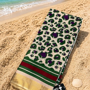 Peut inclure: Un textile rectangulaire présentant un fond crème avec un motif léopard vert et violet. La partie inférieure affiche des rayures horizontales rouge foncé, vertes et crème, terminées par une large bordure dorée métallique et des franges.