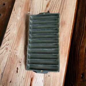 Puede incluir: Un molde para hornear de hierro fundido negro con 12 ranuras individuales. El molde está diseñado para hornear pequeñas porciones individuales de comida.