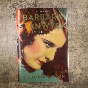 May include: A book cover with a portrait of Barbara Stanwyck. The title is "A Life of Barbara Stanwyck: Steel-True 1907-1940" by Victoria Wilson.