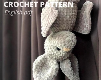 May include: A grey plush bat toy made of soft, textured yarn with small black eyes and a light-coloured nose. The text CROCHET PATTERN English pdf is visible in the upper left corner of the image, indicating a digital document.