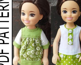 May include: Two dolls wearing handmade dresses. One doll is wearing a green floral print dress with white sleeves. The other doll is wearing a white top with green buttons and a green polka dot skirt. The text "PDF PATTERN" is on the left.