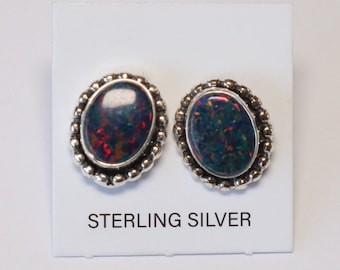 May include: A pair of sterling silver earrings with oval-shaped black opal stones set in a beaded border.