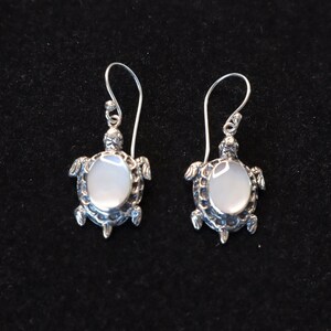 May include: A pair of silver turtle earrings with white mother of pearl inlays.