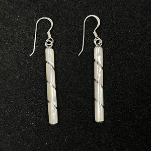 May include: A pair of silver earrings with white mother of pearl drop pieces. The drop pieces are twisted and have a silver stripe running down the center.