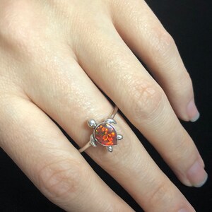 May include: A silver ring with a red opal turtle design.