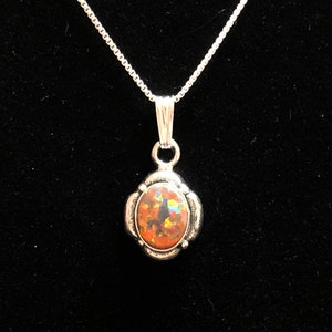 May include: A silver chain necklace with a silver pendant featuring an oval-shaped opal gemstone with a rainbow of colors.