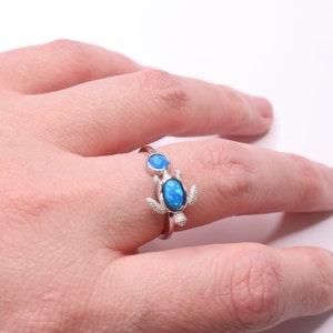 May include: A silver ring with a blue opal turtle design. The turtle has two opals, one on its back and one on its head.