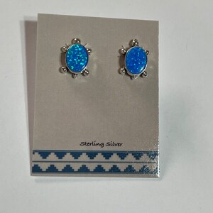 May include: A pair of sterling silver earrings with blue opal stones set in a turtle design.