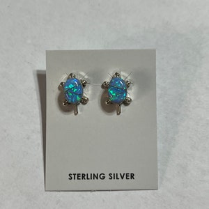 May include: A pair of sterling silver earrings featuring a blue opal turtle design.