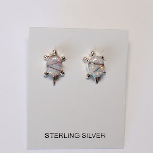 May include: A pair of sterling silver earrings featuring a white opal turtle design.  STERLING SILVER is printed on the card.