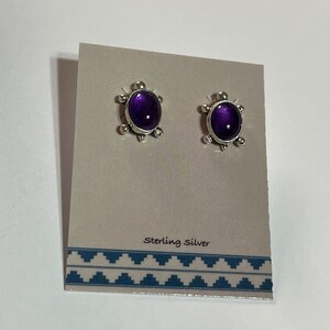 May include: A pair of sterling silver stud earrings with purple amethyst stones. The earrings are displayed on a card with the text "Sterling Silver".