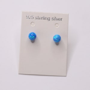 May include: A pair of blue opal stud earrings on a white card with the text "925 sterling silver".