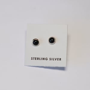 May include: A pair of sterling silver stud earrings with black round stones.