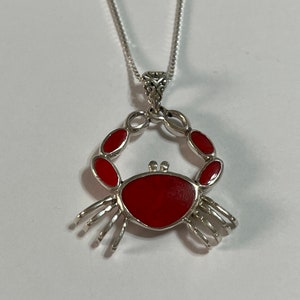 May include: A silver necklace with a red enamel crab pendant.