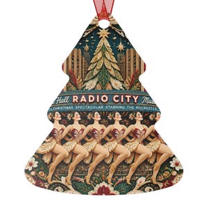 May include: A Christmas tree-shaped ornament featuring a Radio City Music Hall design. The graphic displays a line of dancers in red and gold costumes performing on stage beneath a large Christmas tree, with text reading Radio City Music Hall.