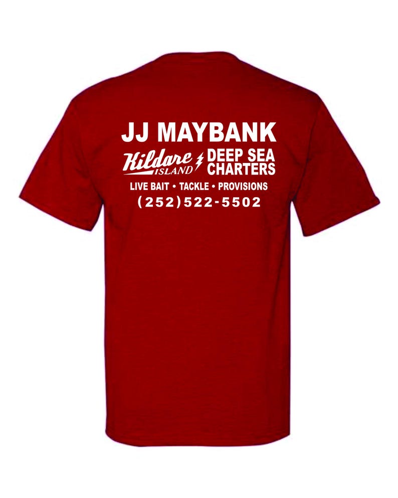 May include: A red short-sleeved t-shirt featuring white text on the back that reads JJ MAYBANK, Kildare ISLAND DEEP SEA CHARTERS, LIVE BAIT TACKLE PROVISIONS, and the phone number (252)522-5502, with a lightning bolt icon between the words.