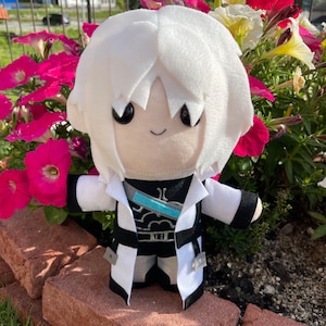 May include: A plush doll with white hair and a black and white outfit. The doll has a smiling face and is standing in front of a vibrant display of pink, red, and yellow flowers. The doll's outfit includes a white coat with black trim.