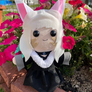 May include: A plush doll with white fur, pink-lined ears, and large black eyes. The doll wears a black dress with a white fur collar and a blue gem. The doll is set against a backdrop of vibrant pink and white flowers.