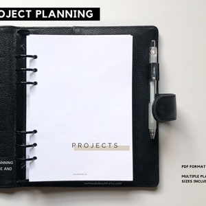 May include: Black leather planner with the text "PROJECT PLANNING" at the top. The planner is open to a white page with the word "PROJECTS" and a pen. Text on the left says "POJECT PLANNING COVER PAGE AND CHECKLIST".