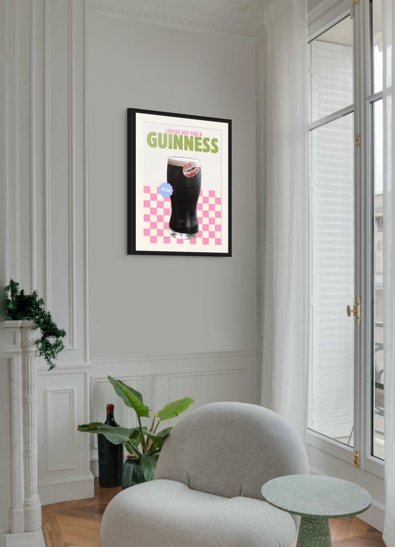 K&ouml;nnte beinhalten: Gerahmter Kunstdruck mit einem Pint Guinness und dem Text "Lovely Day for a Guinness". Das Kunstwerk hat einen rosa-wei&szlig; karierten Hintergrund und einen blauen Aufkleber. Der Druck ist in einem schwarzen Rahmen.