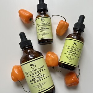 May include: Three amber glass bottles with dropper tops containing organic habanero extract. The bottles have yellow labels with black text that reads "Super Minded Health" and "Organic Habanero". The bottles are surrounded by orange habanero peppers.