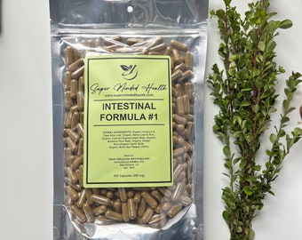 May include: A silver pouch filled with brown capsules labeled "Intestinal Formula #1" by Super Minded Health. The pouch is on a white surface with a green leafy branch in the background.