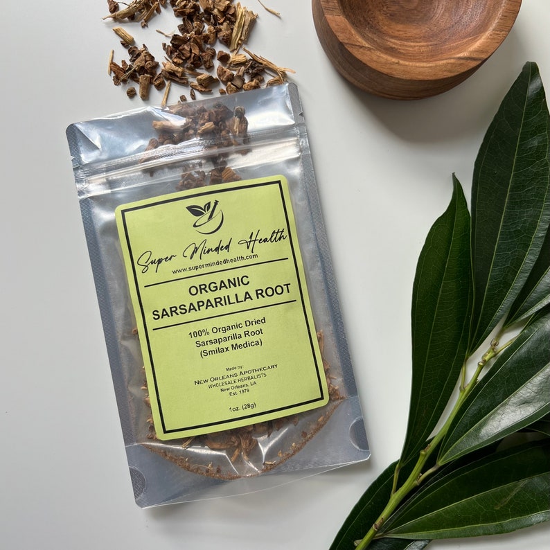 Puede incluir: Una bolsa de pl&aacute;stico transparente con una etiqueta amarilla que contiene 28 gramos de ra&iacute;z de zarzaparrilla seca org&aacute;nica. La etiqueta dice "Super Minded Health" y "Ra&iacute;z de zarzaparrilla org&aacute;nica (Smilax Medica)".