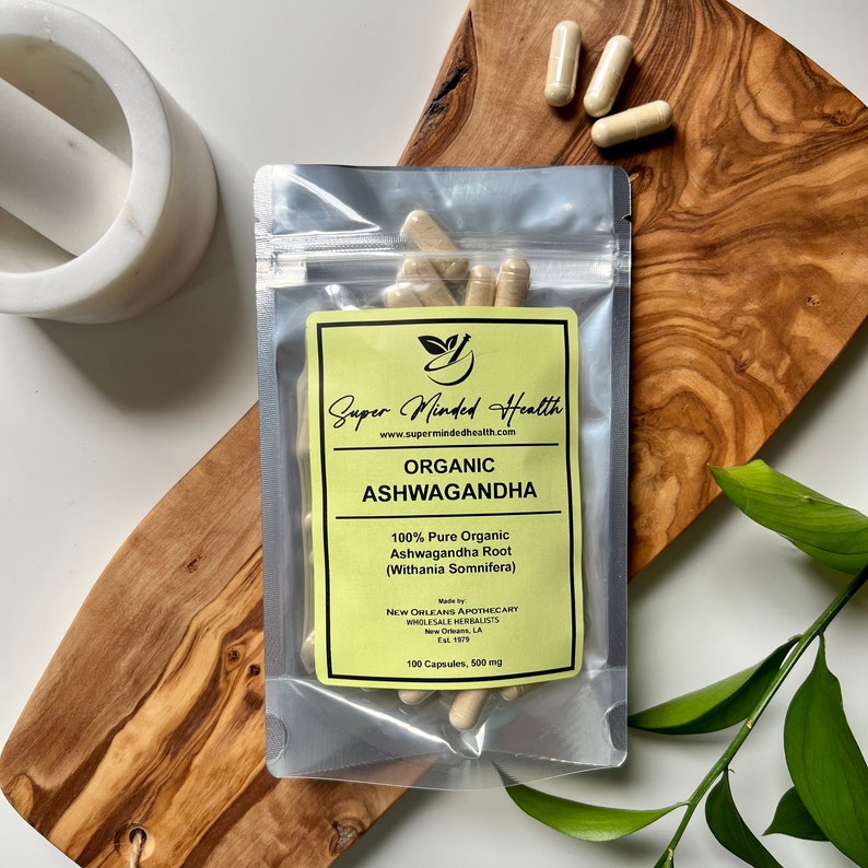 May include: A resealable pouch containing 100 capsules of organic ashwagandha root, labeled "Super Minded Health" with the website address "www.supermindedhealth.com". The label also states "Organic Ashwagandha", "100% Pure Organic Ashwagandha Root (Withania Somnifera)", "Made by New Orleans Apothecary Wholesale Herbalists", "New Orleans, LA Est. 1879", and "100 Capsules, 500 mg".