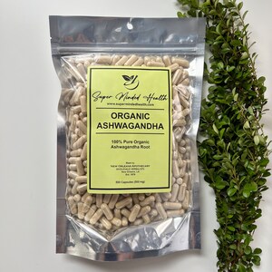 May include: A silver resealable bag filled with 500 capsules of organic ashwagandha root. The bag has a yellow label with the text "Super Minded Health" and "Organic Ashwagandha". The label also states "100% Pure Organic Ashwagandha Root" and "Made by New Orleans Apothecary Wholesale Herbalists Est. 1978".