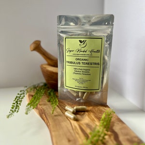 May include: A clear plastic bag containing 50 capsules of a green herbal supplement. The label reads "Super Minded Health" and "Organic Tribulus Terestris". The bag is on a wooden surface.