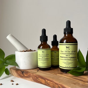 Può includere: Tre bottiglie di vetro ambrato con contagocce contenenti una formula per la prostata. Le bottiglie sono etichettate "Super Minded Health" e "Formula per la prostata maschile". La bottiglia più grande è da 4 oz. Le bottiglie sono su una superficie di legno con un mortaio e un pestello bianchi e foglie verdi.