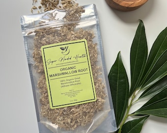 Könnte beinhalten: Ein transparenter Plastikbeutel gefüllt mit getrockneter, hellbrauner Eibischwurzel. Der Beutel hat ein gelbes Etikett mit dem Text "Super Minded Health" und "Organic Marshmallow Root". Das Etikett enthält auch den Text "100% Organic Dried Marshmallow Root (Althaea Officinalis)" und "2 oz (56g)".