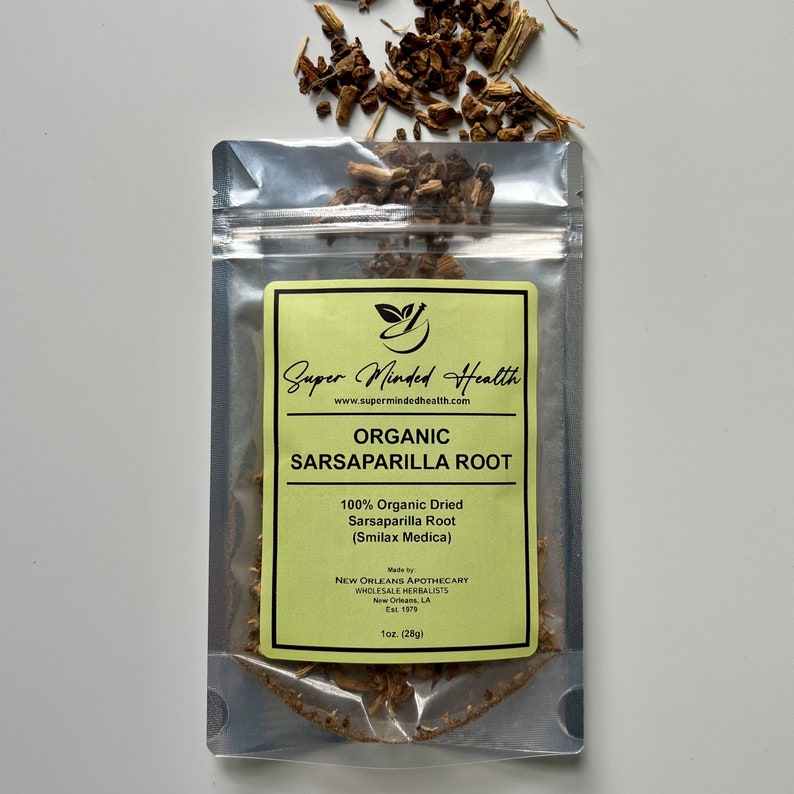 Puede incluir: Una bolsa plateada resellable que contiene ra&iacute;z de zarzaparrilla seca. La etiqueta amarilla y blanca dice "Super Minded Health", "Organic Sarsaparilla Root", "100% Organic Dried Sarsaparilla Root (Smilax Medica)" y "Made by New Orleans Apothecary Wholesale Herbalists Est. 1979 1oz. (28g)"