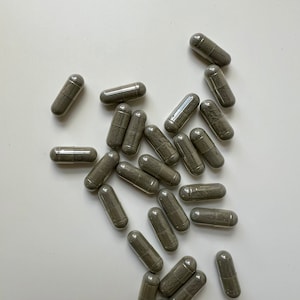 Puede incluir: Un mont&oacute;n de c&aacute;psulas grises sobre una superficie blanca. Las c&aacute;psulas son todas del mismo tama&ntilde;o y forma, y est&aacute;n dispuestas en un patr&oacute;n aleatorio.