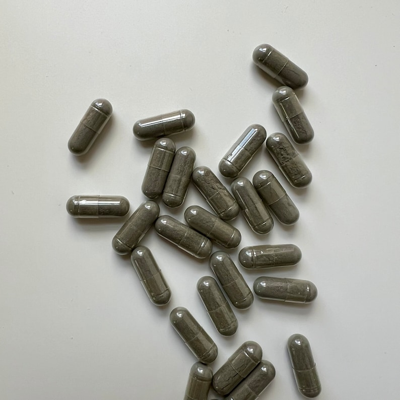 Puede incluir: Un mont&oacute;n de c&aacute;psulas grises sobre una superficie blanca. Las c&aacute;psulas son todas del mismo tama&ntilde;o y forma, y est&aacute;n dispuestas en un patr&oacute;n aleatorio.